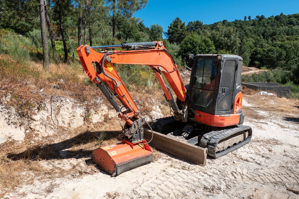 Mini crawler excavator cleaning rural road verges